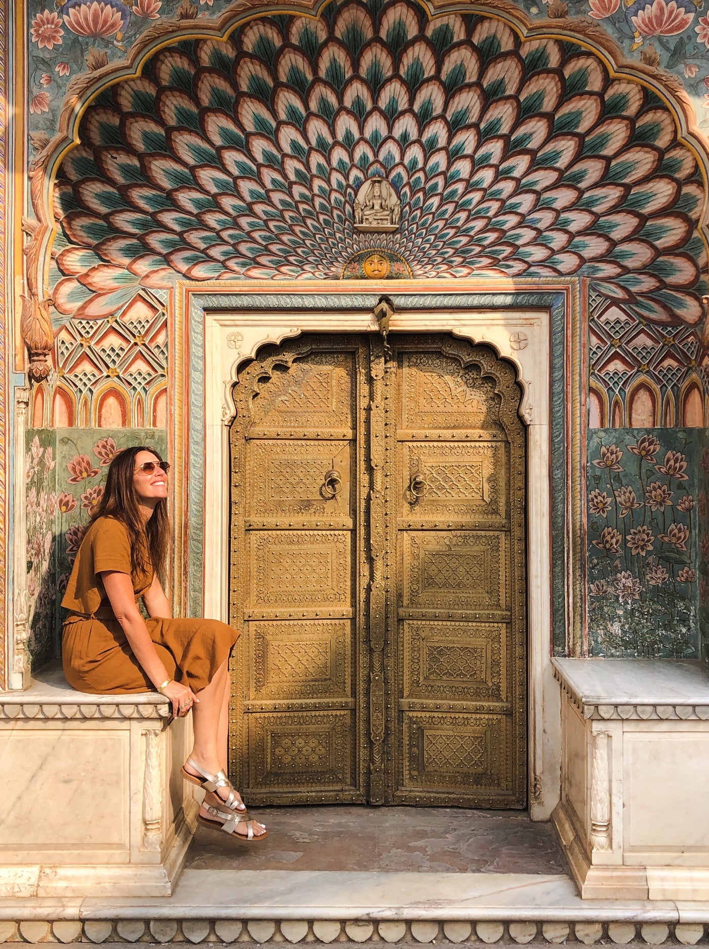 Woman traveler poses elegantly in front of a beautifully designed door, adding a touch of sophistication to her look