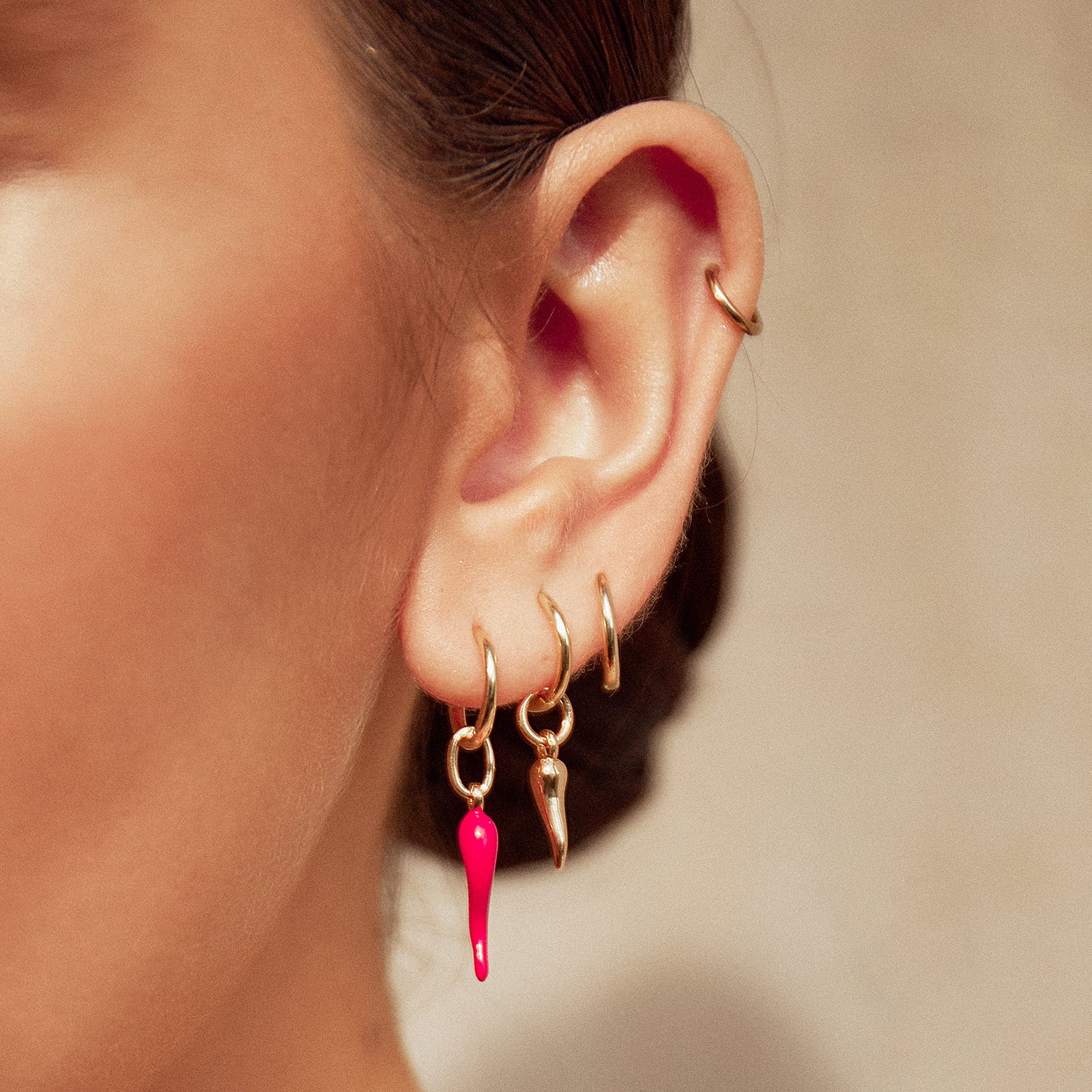 Close-up of woman's ear adorned with multiple piercings and stylish earrings