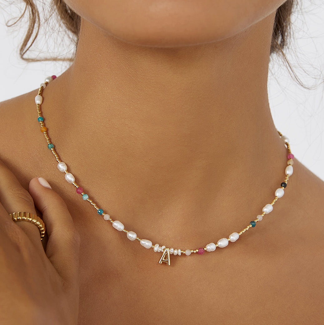 Arms Of Eve delicate beaded gemstone and pearl necklace featuring a letter charm, adorned with pearls and beads