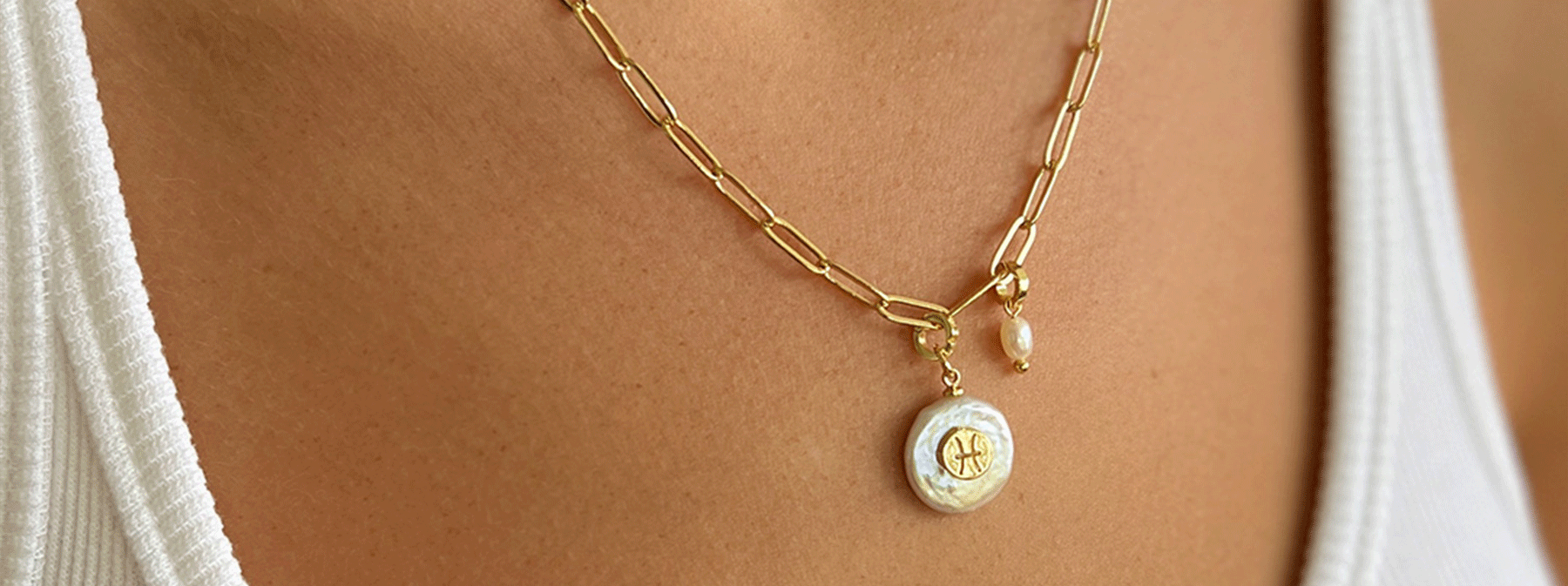Arms Of Eve Charm builder necklace modeled by woman with a gold chain necklace featuring a delicate pearl pendant