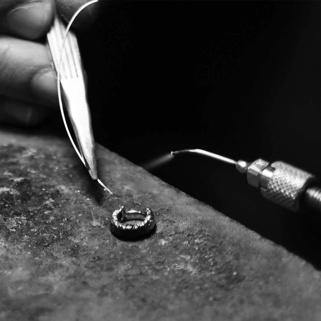 View of micro torch applying heat to a metal ring by a skilled artisan crafting exquisite Arms Of Eve jewelry pieces